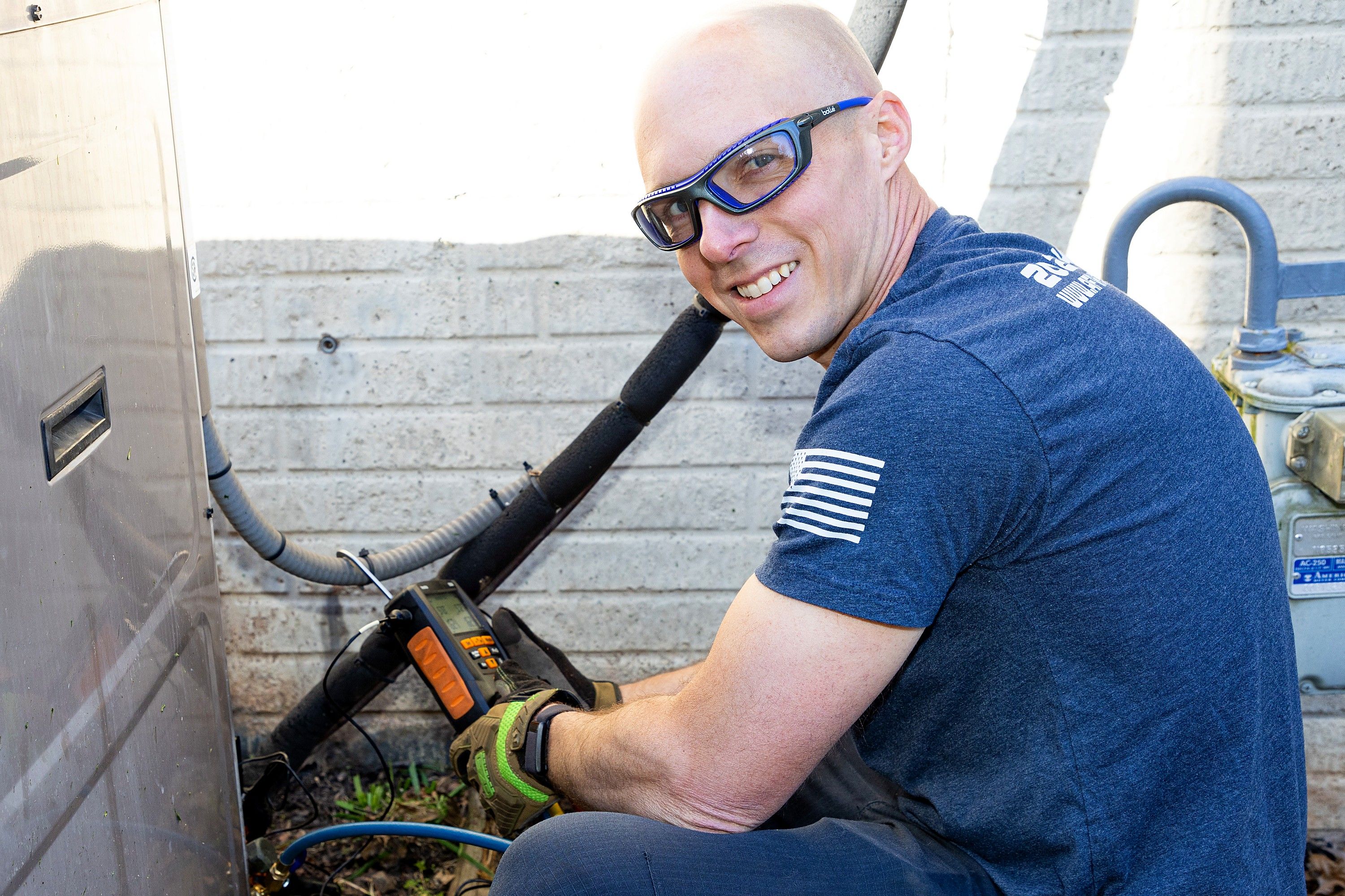 Jim Higgins smiling while servicing an outdoor HVAC unit